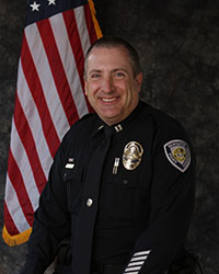 Jeff Williams wearing full dress uniform poses in front of American flag.
