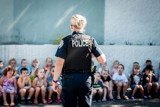 BPD officer with her back to the camera presents to a large group of young children.