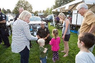 BPD officer kneels down to talk with young children with NAC volunteers in attendance.